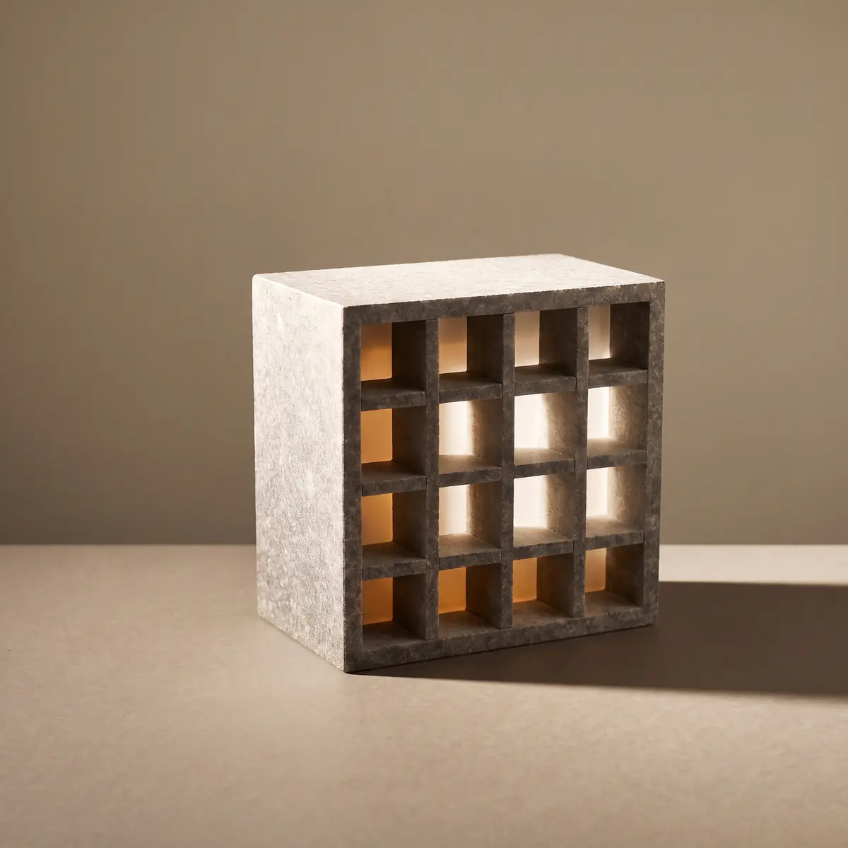 Sur une table, un bloc de granit percé de seize alvéoles éclairées de l'intérieur.